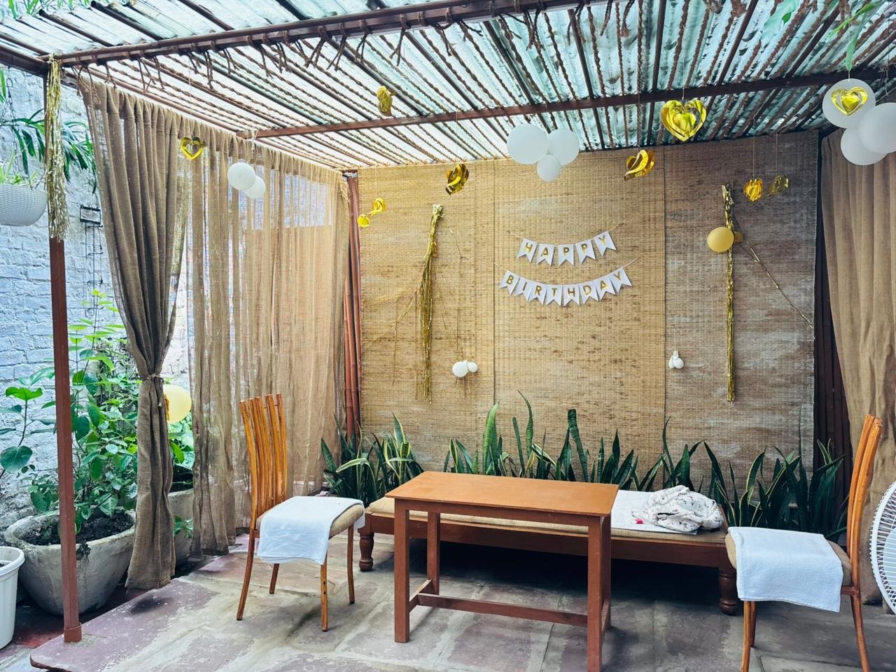 A birthday setup at Bageecha — burlap drapes, gold balloons and a Happy Birthday banner
